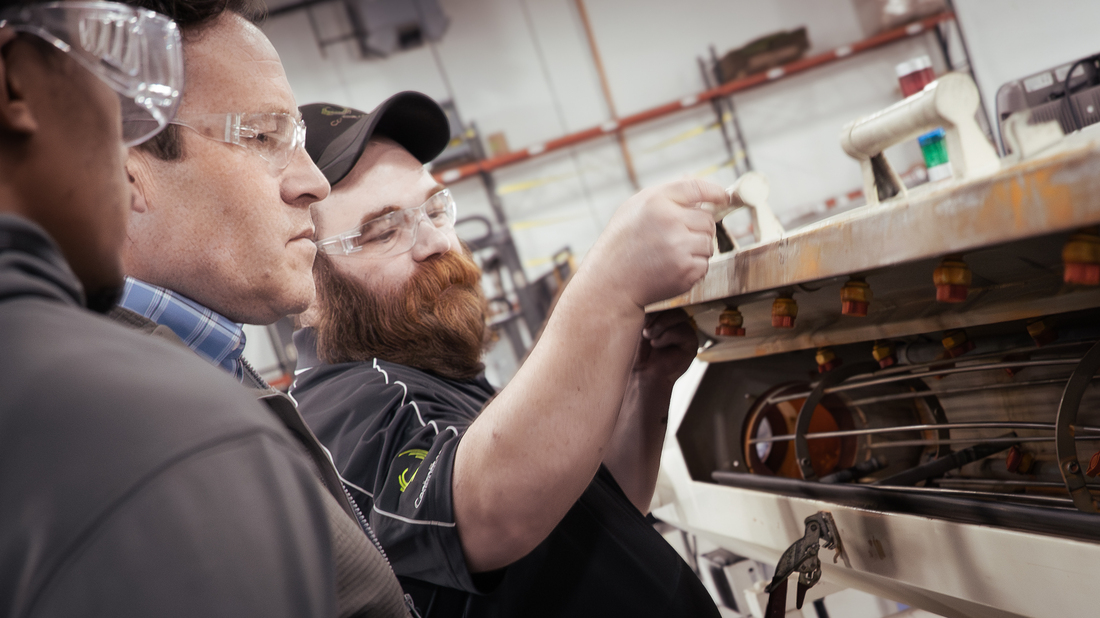 three men look at machinery 